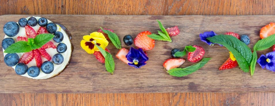 Fresh berries and edible flowers on a wooden board