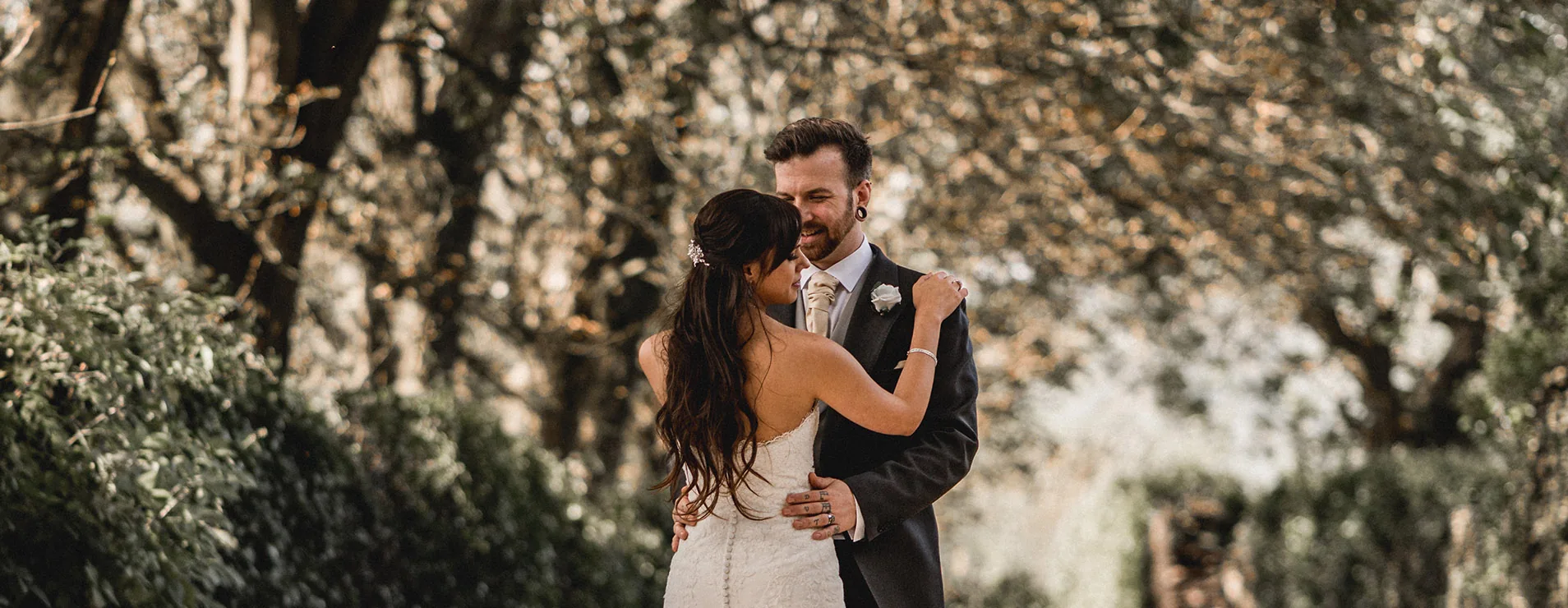 A wedding couple embracing in the grounds of Llechwen Hall